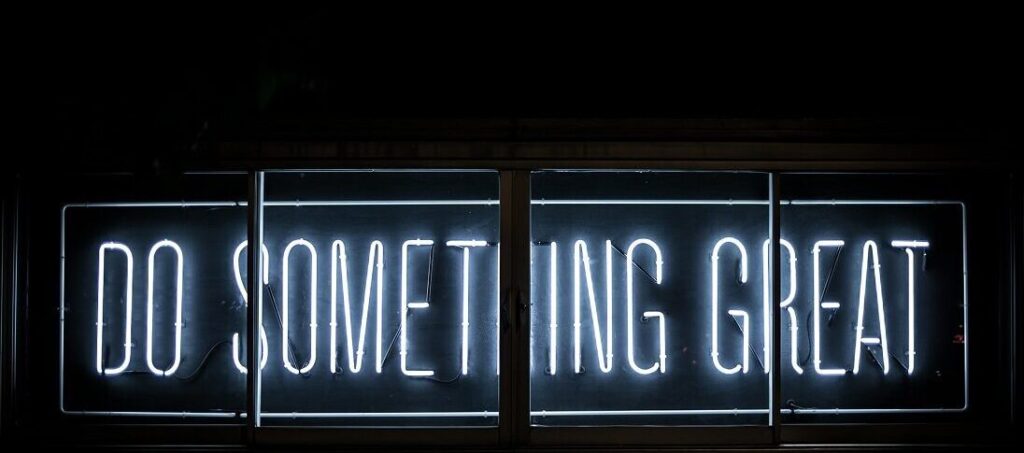 Do something great written in white neon lights on a black background.